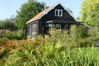Groen houten huis met rood dak in Engelse tuin