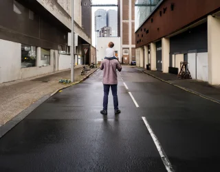 man with child on his back in the middel of building in a city